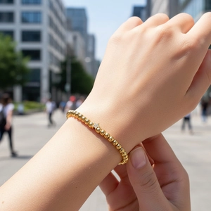 Close-up of a gold beaded bracelet with a sparkling star pendant worn on a wrist