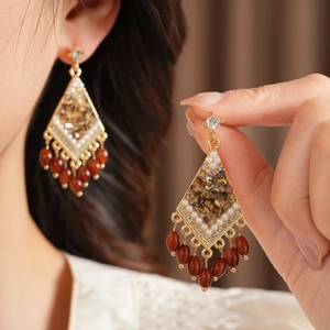 Detalle de pendientes vintage en forma de rombo con borlas de vidrio y diamantes