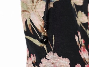 Macro detail of braided drawstring and black bead on pink floral linen dress fabric