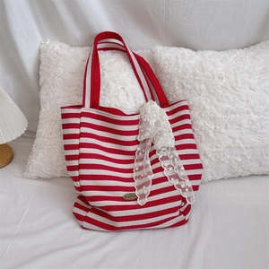 Detail of red and white striped canvas tote bag with a white lace bow and metal tag
