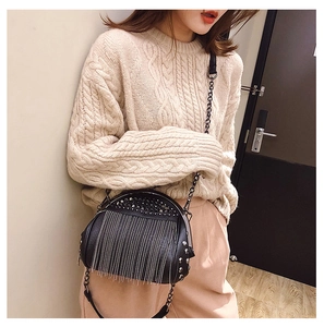 Detail of black punk shell bag with silver rivets and long metal chain fringe over knitwear