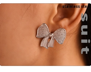 Macro view of brushed silver bow stud earring in stainless steel on model's ear