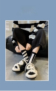 Detail of plush white fleece criss-cross sandals paired with black and white striped socks