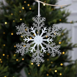 Hollow acrylic snowflake Christmas tree ornament with glitter finish on warm bokeh background