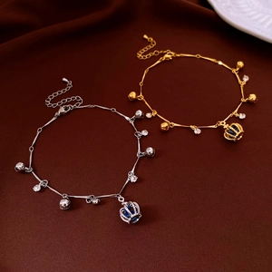 Détail de bracelets or et argent avec couronne, clochette et cristal bleu sur soie