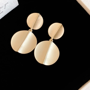 Detail of gold brushed metal earrings on black velvet with a 'for you' gift card