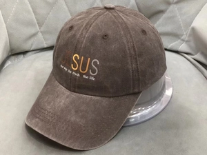 Close-up of washed cotton baseball cap with Jesus slogan on grey textured background