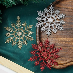 Close-up of glittery snowflake ornaments in gold, silver, and red on a rustic tray