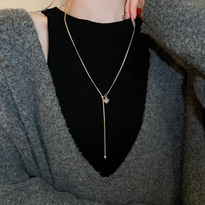 Detailed view of a gold-plated Y-shaped necklace with a square zircon pendant and beads