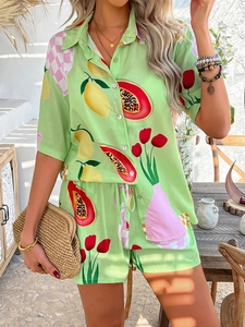 Detail of green two-piece resort set with citrus and tulip prints on a sunny terrace