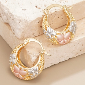 Elegante gouden vlinderoorringen met roze en zilveren vleugels op een stenen basis