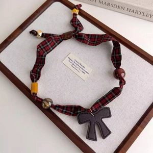 Macro shot of red plaid fabric necklace with wooden beads and a fabric bow pendant
