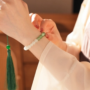 Close-up of beaded jade chalcedony bracelet with green tassel on a female wrist