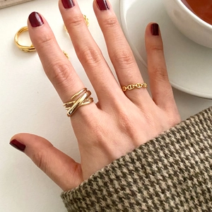 Close-up of gold plated woven and link rings worn on hand in a stylish setting