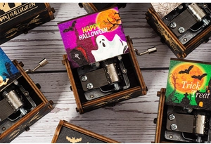 Close-up of three hand-cranked wooden Halloween music boxes with spooky festive patterns