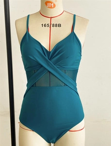 Detail of teal one-piece swimsuit featuring cross-over bust and sheer mesh paneling