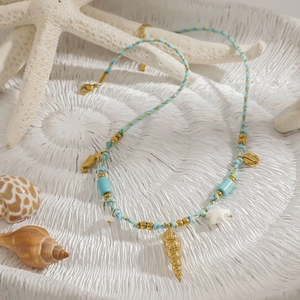 Détail du collier de plage avec perles turquoise et breloques d'animaux marins dorés