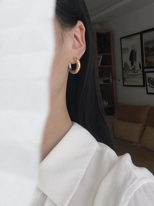 Macro shot of two-tone metallic hoop earrings on model with polished silver and gold finish