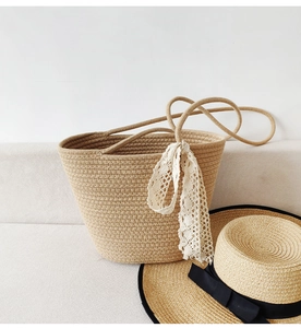Detail of khaki woven cotton rope tote bag with lace ribbon and summer straw hat