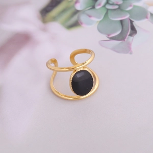 Détail d'une bague double dorée avec une pierre noire ovale polie incrustée