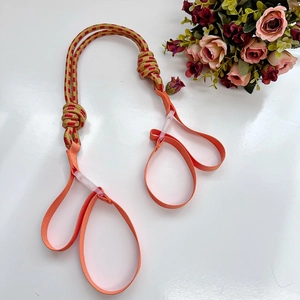Detailed close-up of pink and tan woven yoga mat strap with adjustable double ring buckles