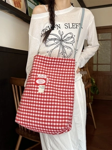 Red and white gingham plaid tote bag with crossbody strap shown in a lifestyle setting