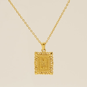 Détail d'un pendentif rectangulaire plaqué or 18K avec gravure évidée de la lettre M