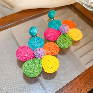 Close-up of colorful woven flower earrings featuring vibrant raffia petals in a summer style
