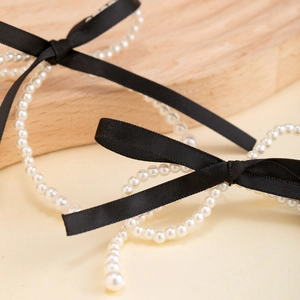 Elegant white pearl strand earrings featuring black silk ribbon bows and crystal accents