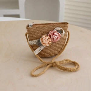 Detailed close-up of straw woven crossbody bag with lace ribbon and floral decorations