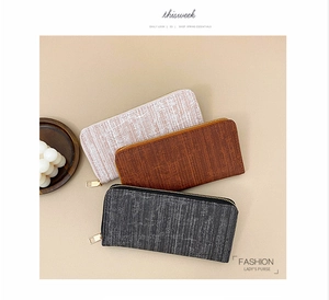 Detailed flat lay of long textured wallets in pink, brown, and dark grey with zip closures