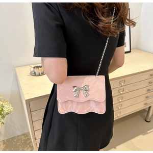 Détail du sac bandoulière rose avec texture marbrée, rabat vague et nœud argenté