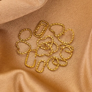 Twisted gold stainless steel open rings in various shapes on luxury silk fabric