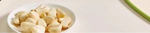 Close-up of fresh peeled garlic cloves on a white plate for food preparation