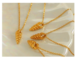 Detail of four golden spiral shell necklaces displayed on a pearlescent plate