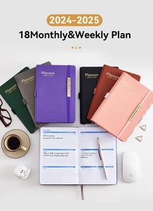 Flat lay of colorful 18-month faux leather planners with accessories on a grey surface