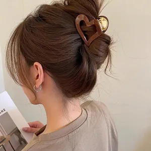 Brown heart-shaped acetate claw clip for high ponytail styling with gold metal spring