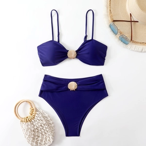 Flat lay of navy blue bikini set with gold shell buckles and beach accessories