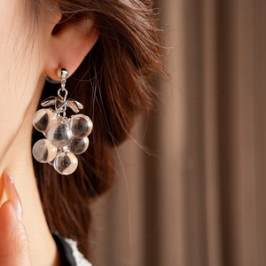 Close-up of model wearing crystal grape tassel earrings with clear beads and silver finish