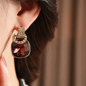 Vintage style gold earrings featuring a large square burgundy gemstone and micro-pavé crystals