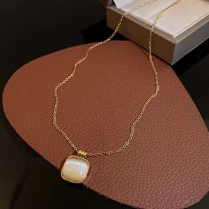 Détail du pendentif carré en opale blanche sur une chaîne dorée en acier au titane