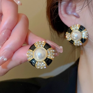 Close-up of vintage black enamel earrings with pearl center and sparkling rhinestones