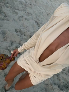 Detailed top-down view of beige long-sleeve mini dress with deep V-neck and waist ruching