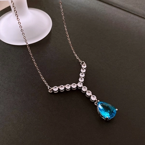 Detail of silver chain with blue teardrop zircon pendant and inlaid white crystals