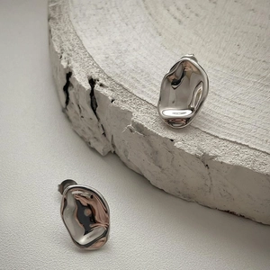 Detailed view of silver minimalist irregular liquid metal earrings on stone
