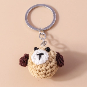 Detail of handcrafted crochet puppy keychain with beige yarn and silver metal ring