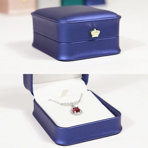 Navy blue jewelry box with crown decor and red gemstone necklace set inside