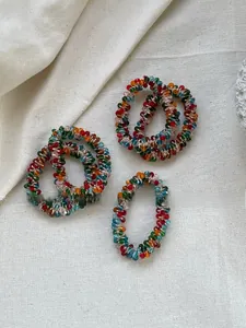 Detail of five colorful crystal beaded hair ties with elastic spiral design on linen fabric