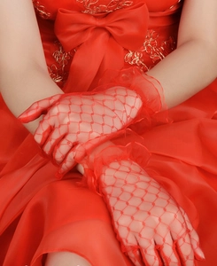 Detail of red mesh lace gloves with elegant ruffled cuffs and vintage polka dot pattern