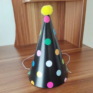 Mini birthday party hat with colorful polka dots on black background and yellow pom-pom